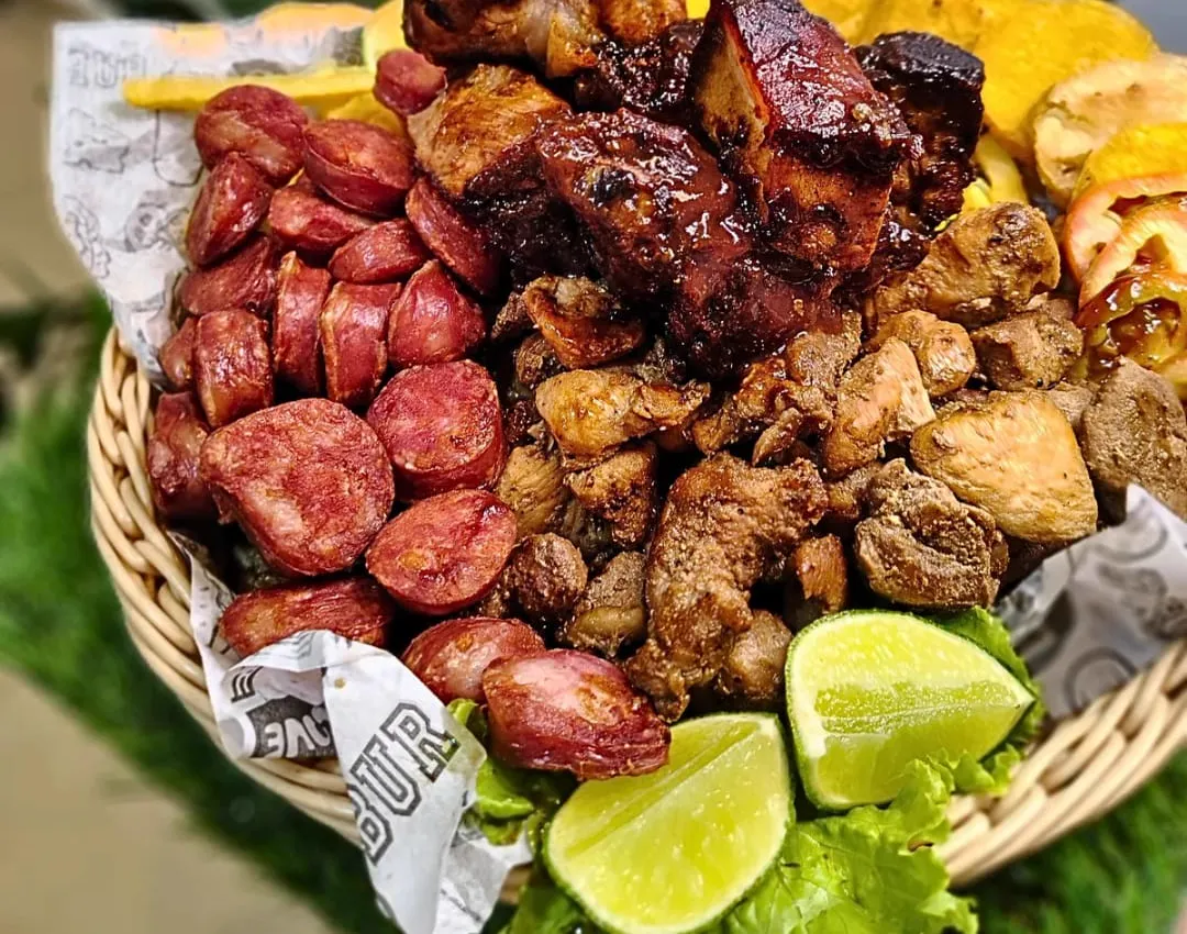 Cesta com linguiça fatiada, costelinha, frango e limão